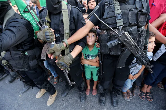 Palestinian boys stand next to Hamas militants as they take part in a military show against Israel's newly-installed security measures at the entrance to the al-Aqsa mosque compound, in Khan Younis, in the southern Gaza Strip on July 20, 2017. (Photo by Ibraheem Abu Mustafa/Reuters)