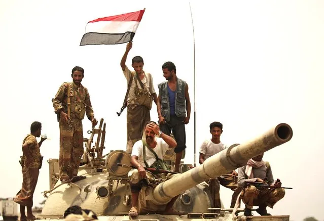 Yemeni army soldiers and tribesmen wave a flag as they drive through  Zinjibar, Yemen, after retaking the city from al-Qaida militants on June 14, 2012