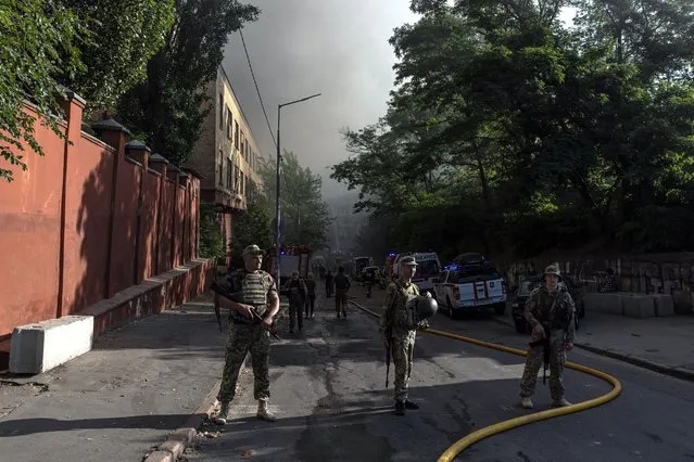 Ukrainian soldiers stand guard on a site following Russian airstrikes in the Shevchenkivskiy district of Kyiv (Kiev), Ukraine, 26 June 2022. Multiple airstrikes hit the center of Kyiv in the morning. Russian troops on 24 February entered Ukrainian territory, starting the conflict that has provoked destruction and a humanitarian crisis. (Photo by Roman Pilipey/EPA/EFE)