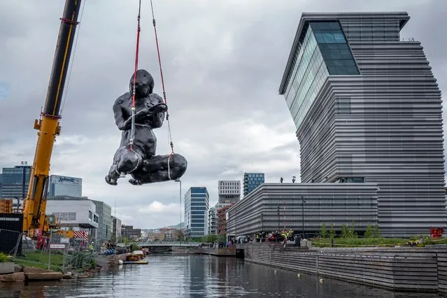 The sculpture “The Mother” by British artist Tracey Emin is moved by crane to its position outside The Munch Museum in Oslo, Norway, on June 2, 2022. The nine-metre-high bronze sculpture weighing about 18 tonnes was shipped in parts from London and arrived with delay in Oslo. It will be placed at the Oslo waterfront, where it can be viewed by the public. The piece was created to honour the artist's mother and depicts a woman kneeling over an invisible child. (Photo by Heiko Junge/NTB/AFP Photo)