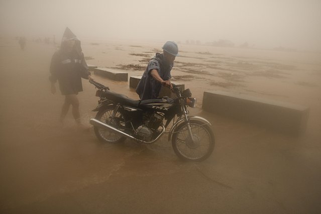 A resident pushes his motorcycle along floods from a swollen river caused by heavy rains from Typhoon Toraji in Ilagan City, Isabela province, northern Philippines on Monday, November 11, 2024. (Photo by Noel Celis/AP Photo)