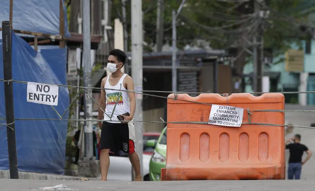 A man wearing a protective mask walks past an area cordoned off for an enhanced community quarantine aimed to prevent the spread of the new coronavirus in Manila, Philippines, Tuesday, March 24, 2020. (Photo by Aaron Favila/AP Photo)