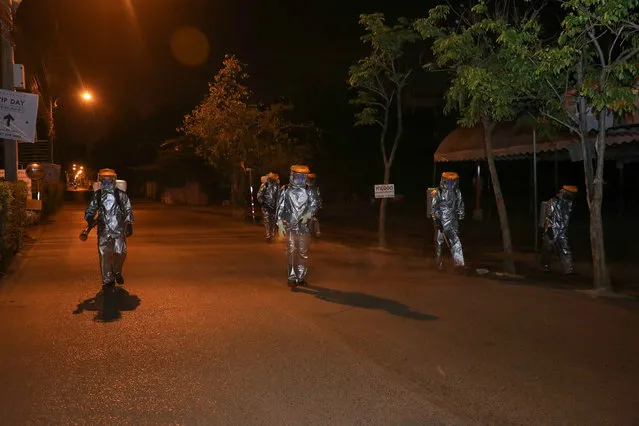 This handout photo taken and released on March 26, 2020 by the Royal Thai Army shows soldiers wearing protective clothing and spraying disinfectant as they walk down a road amid preventive measures to stop the spread of COVID-19 coronavirus in Bangkok. (Photo by Royal Thai Army/Handout via AFP Photo)