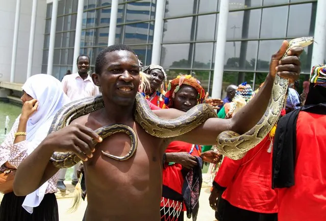 A Sudanese man carries a snake as demonstrators rally outside the Al-Sadaka hall in the capital Khartoum, on August 14, 2022, during a meeting of “The Call of Sudan's People” political initiative. Hundreds of Sudanese rallied in support of the political initiative backed by army chief Abdel Fattah al-Burhan who led last year's military coup, AFP correspondents said. (Photo by AFP Photo/Stringer)