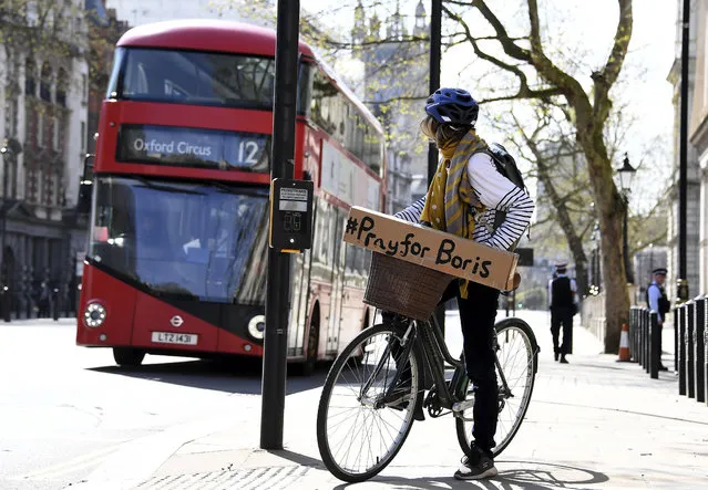 A woman shows a sign on her bicycle as British Prime Minister Boris Johnson is in intensive care fighting the coronavirus in London, Tuesday, April 7, 2020. Johnson was admitted to St Thomas' hospital in central London on Sunday after his coronavirus symptoms persisted for 10 days. Having been in hospital for tests and observation, his doctors advised that he be admitted to intensive care on Monday evening. (Photo by Alberto Pezzali/AP Photo)