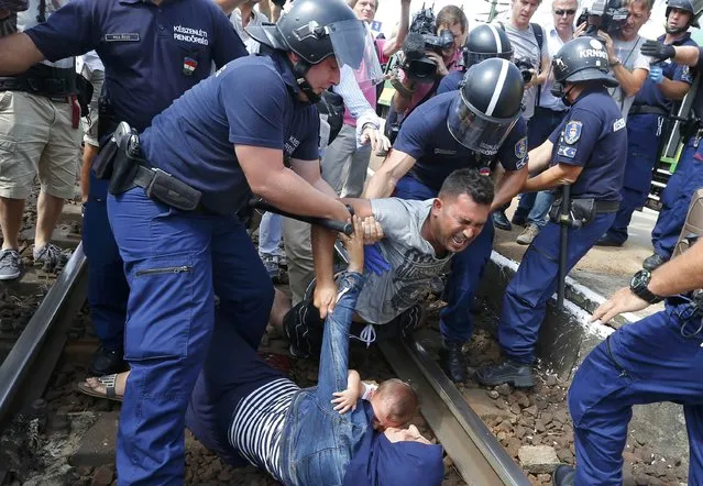 Hungarian policemen detain migrants on the tracks as they wanted to run away at the railway station in the town of Bicske, Hungary, September 3, 2015. (Photo by Laszlo Balogh/Reuters)