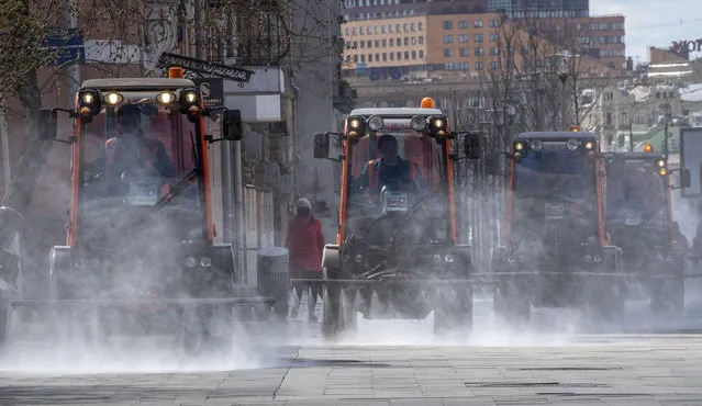 Municipal vehicles spray disinfectant on the deserted streets of central Moscow, on April 12, 2020 during a strict lockdown in Russia to stop the spread of the COVID-19, caused by the novel coronavirus. (Photo by Yuri Kadobnov/AFP Photo)