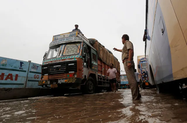 A policeman directs the vehicles in a waterlogged highway after heavy rains in Gurugram, previously known as Gurgaon, on the outskirts of New Delhi, India, July 29, 2016. (Photo by Adnan Abidi/Reuters)