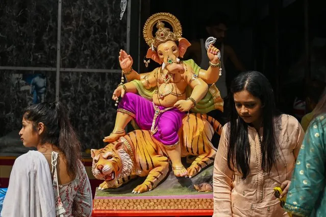 Hindu devotees prepare to carry an idol of the elephant-headed Hindu deity Ganesha on the first day of ten-day “Ganesh Chaturthi” festival in Mumbai on August 31, 2022. (Photo by Punit Paranjpe/AFP Photo)