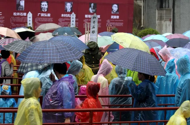 Tourists line up to slap dummies at a scenic spot, in Luoyang, Henan province, September 4, 2015. The scenic spot set up kneel-down dummies dressed as Japanese war criminals to mark the 70th anniversary of the end of World War Two, according to local media. (Photo by Reuters/Stringer)