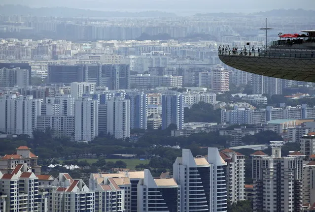 People look out from the observation tower of the Marina Bay Sands amongst public and private residential apartment buildings in Singapore, February 22, 2016. (Photo by Edgar Su/Reuters)
