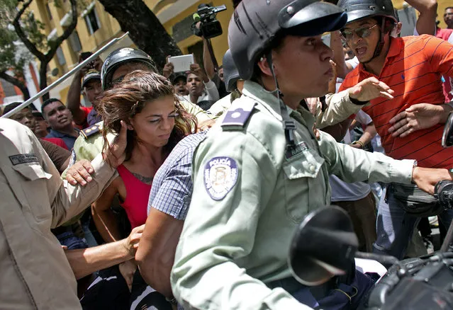 A woman is detained by national police during clashes between supporters of jailed opposition leader Leopoldo Lopez and government loyalists outside the courthouse in Caracas, Venezuela, Thursday, September 10, 2015. Supporters of a high-profile jailed Venezuelan opposition leader clashed with government loyalists Thursday outside a Caracas courthouse in anticipation of an impending verdict. (Photo by Ariana Cubillos/AP Photo)
