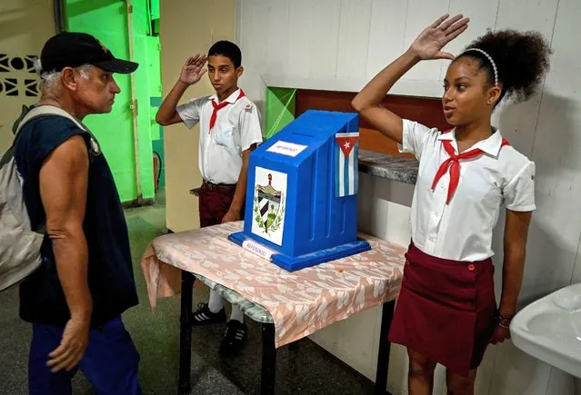 Students salute after a man cast his vote at a polling station during the new Family Code referendum in Havana on September 25, 2022. Cubans on Sunday are voting in a landmark referendum on whether to legalize same-s*x marriage and adoption, allow surrogate pregnancies, and give greater rights to non-biological parents. (Photo by Adalberto Roque/AFP Photo)