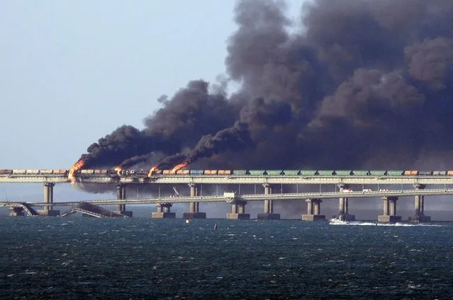 Black smoke billows from a fire on the Kerch bridge that links Crimea to Russia, near Kerch, on October 8, 2022. Moscow announced on October 8, 2022 that a truck exploded igniting a huge fire and damaging the key Kerch bridge – built as Russia's sole land link with annexed Crimea – and vowed to find the perpetrators, without immediately blaming Ukraine. (Photo by AFP Photo/Stringer)