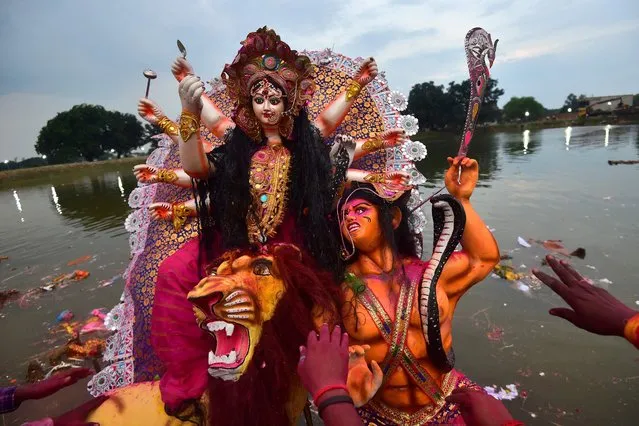 Devotees immerse an idol of the Hindu Goddess Durga in a pond during the final day of the Durga Puja festival on the outskirts of Allahabad on October 5, 2022. (Photo by Sanjay Kanojia/AFP Photo)