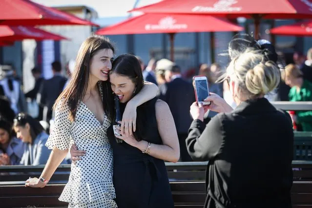 Two pals giggle as they come in close while their friend takes a snap on her phone on 2017 Derby Day at Flemington Racecourse on November 4, 2017 in Melbourne, Australia. (Photo by Splash News and Pictures)