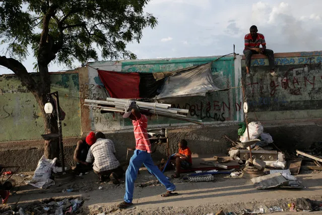 A man carrying pipes walks past a scrap metal stand along a street in Port-au-Prince, Haiti, July 14, 2016. (Photo by Andres Martinez Casares/Reuters)