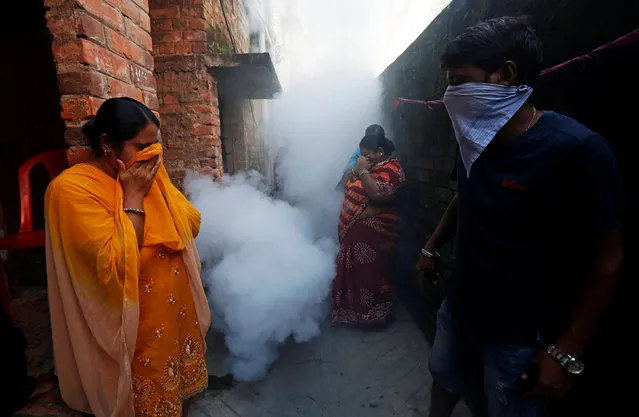People cover their faces as a municipal worker fumigates a slum area to prevent the spread of dengue fever and other mosquito-borne diseases in Kolkata, November 4, 2017. (Photo by Rupak De Chowdhuri/Reuters)