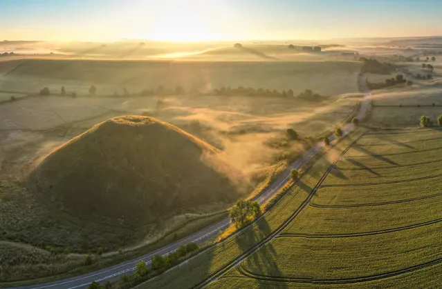 Daybreak and low-lying mist surrounds the fields around the ancient man-made mound of Silbury Hill in Wiltshire, UK on what promises to be a warm summer's day on July 8, 2022. (Photo by Lee Thomas/The Times)