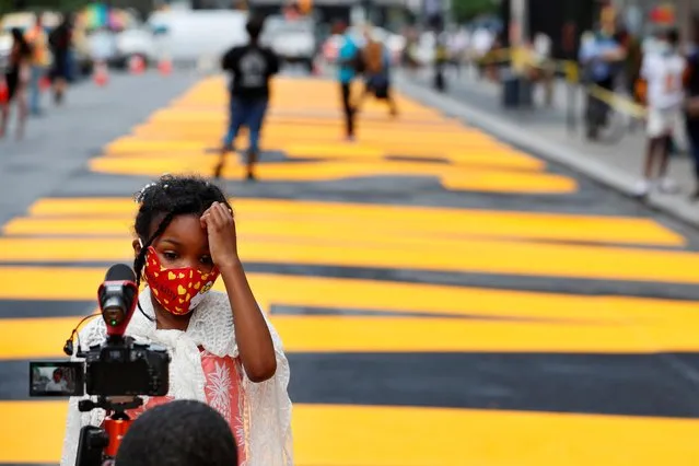Harmony Beckford speaks to a camera as she stands in front of a large “Black Lives Matter” banner painted on a street near the Brooklyn borough hall in New York City, New York, June 26, 2020. (Photo by Lucas Jackson/Reuters)