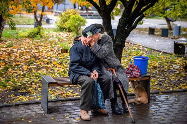 An elderly couple hug each other while sitting on a bench in the frontline town of Bakhmut, in eastern Ukraine's Donetsk region, on October 27, 2022, amid Russia's invasion of Ukraine. The eastern Ukraine town, known for its salt mines and vineyards, has been under attack for months by Russian forces, who are mostly on the defensive in other regions across Ukraine. (Photo by Dimitar Dilkoff/AFP Photo)