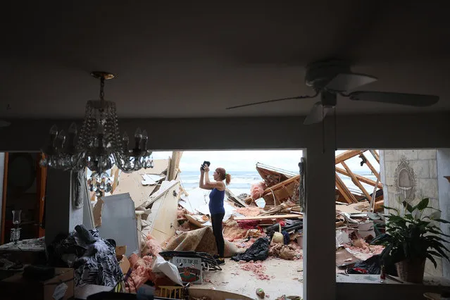 Lisa Lavigna takes pictures of her mother Nina Lavigna's home after it partially toppled onto the beach as Hurricane Nicole came ashore on November 10, 2022 in Daytona Beach, Florida. Nicole came ashore as a Category 1 hurricane before weakening to a tropical storm as it moved across the state. (Photo by Joe Raedle/Getty Images)