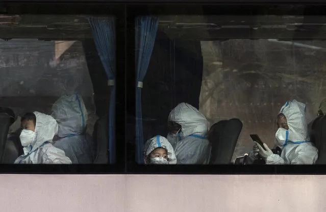 Residents, including children, wear protective clothing and masks as they wait on a bus outside a residential compound before leaving, as part of epidemic control to prevent the spread of COVID-19, on November 15, 2022 in Beijing, China. Though the government recently revised its COVID strategy, it has said it will continue to stick to its strict zero tolerance policy with mandatory testings, quarantines and lockdowns in many areas in an effort to control the spread of the virus. (Photo by Kevin Frayer/Getty Images)
