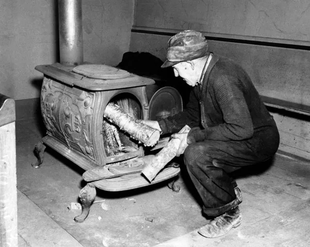 Man adds wood to stove during Town Meeting in Yarmouth, Maine, December 1, 1944. (Photo by AP Photo)
