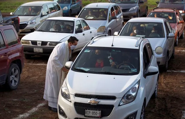 Father Tomas Torres Najera, Vicar of the Cuernavaca Diocese wearing a protective mask in the midst of the new coronavirus pandemic, greets parishioners sitting in their cars before Mass at a drive-in cinema in Cuernavaca, Morelos, in Mexico, Sunday, August 2, 2020. Parishioners can listen to the Mass on their car radios. (Photo by Marco Ugarte/AP Photo)
