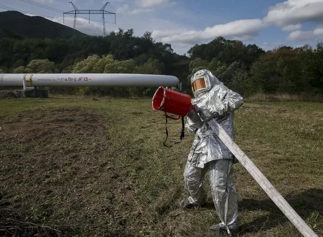 A firefighter extinguishes fire as he participate in a drill simulating a fire incident near a gas compressor station near the village of Volovets, western Ukraine, October 7, 2015. Ukraine might start buying natural gas from Russia before a final winter gas agreement is signed, news agency Interfax Ukraine quoted Ukrainian Energy Minister Volodymyr Demchyshyn as saying on Wednesday. (Photo by Gleb Garanich/Reuters)