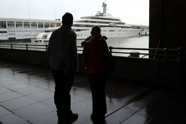 A couple looks out at the Eclipse, reported to be the largest private yacht in the world, which is docked at a pier in New York on February 19, 2013 in New York City. The boat, which measures 557ft in length and is estimated to cost 1.5 billion US dollars, is owned by Russian billionaire Roman Abramovich and arrived into New York on Wednesday.  (Photo by Spencer Platt)