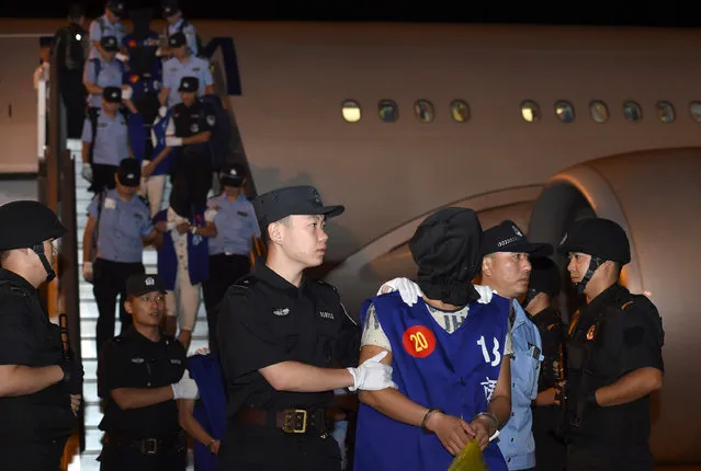 In this photo released by China's Xinhua News Agency, hooded internet fraud suspects are escorted off a plane by Chinese police at Lukou International Airport in Nanjing in eastern China's Jiangsu Province after being deported from Cambodia, Tuesday, September 20, 2016. Cambodia has deported 13 Taiwanese and 50 Chinese suspects to China, a senior police official said Wednesday. (Photo by Han Yuqing/Xinhua via AP Photo)