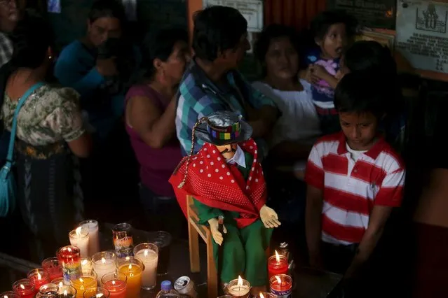 A child stands next on an effigy of San Simon in the church in his honor in Iztapa, Chimaltenango, Guatemala, October 28, 2015. (Photo by Jorge Dan Lopez/Reuters)