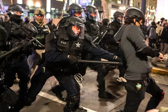 An Oregon State Trooper hits a protester with his baton while dispersing a crowd of black bloc protesters on November 4, 2020 in Portland, Oregon. Multiple protests, some peaceful and others violent, broke out in Portland as the presidential election remained undecided. (Photo by Nathan Howard/Getty Images)