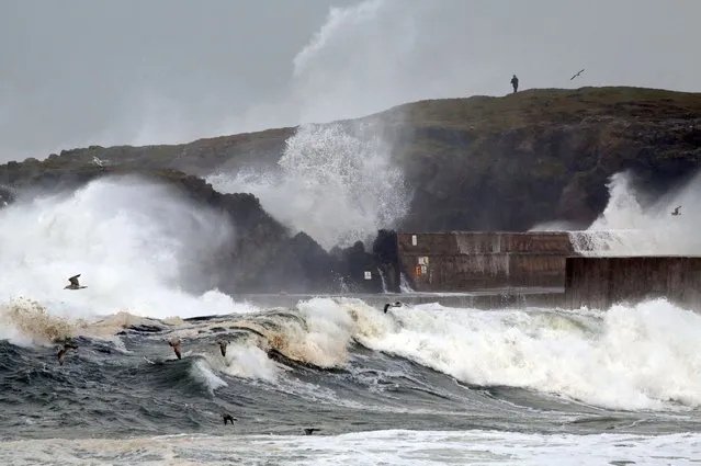 Large waves batter the sea barriers during stormy weather in Portstewart in Northern Ireland, on December 10, 2014. Energy companies were working Wednesday to restore power to around 17,500 homes in the west of Scotland affected by  stormy weather and high winds. (Photo by Paul Faith/AFP Photo)