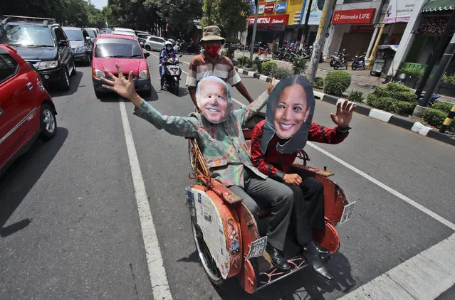 Indonesian men wearing masks of President-elect Joe Biden and Vice President-elect Kamala Harris wave as they sit on a tricycle as they celebrate their win in the U.S. presidential election, in Solo, Centra Java, Indonesia on Sunday, November 8, 2020. (Photo by AP Photo/Stringer)