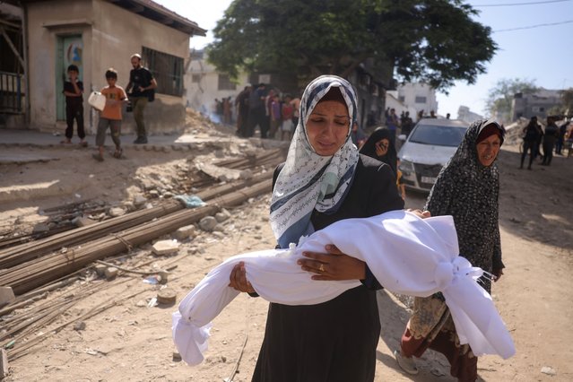 A Palestinian woman carries the body of a child outside Shifa hospital in Gaza City where casualties of Israeli fire were transported ahead of their funerals, on August 29, 2025, as the war between Israel and the Hamas militant movement continues. The Israeli military declared Gaza City “a dangerous combat zone” on August 29, as it prepared to conquer the Palestinian territory's largest city after almost two years of war. (Photo by Bashar Taleb/AFP Photo)