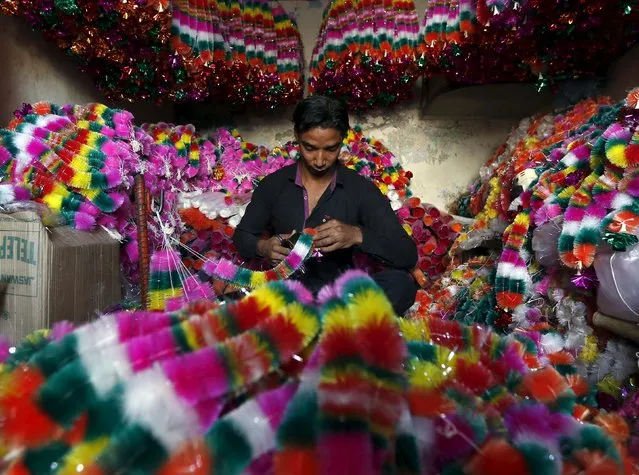A vendor makes artificial garlands for sale inside his shop ahead of the Hindu festival of Diwali in Ahmedabad, India, October 29, 2015. Flowers are offered to Hindu gods and goddesses on the occasion of Diwali, the annual festival of lights that will be celebrated across the country on November 11. (Photo by Amit Dave/Reuters)