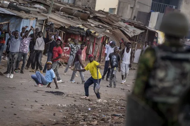 A protester throws a rock at police as they demonstrate in the Kibera slum of Nairobi, Kenya Monday, March 20, 2023. (Photo by Ben Curtis/AP Photo)