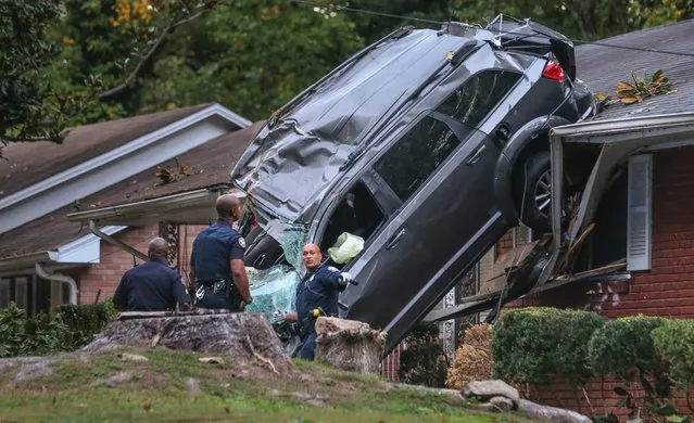 Atlanta police work at the scene of a car crash after a teen was ejected from a stolen SUV early Tuesday, October 18, 2016 in Atlanta after he lost control of the vehicle and landed on a home in southwest Atlanta, police said. The driver, who was in stable condition at an area hospital, was driving southbound on Maxwell Drive at a high rate of speed when the teen lost control of the SUV, Atlanta police Sgt. Dorian Graham said. (Photo by John Spink/Atlanta Journal-Constitution via AP Photo)