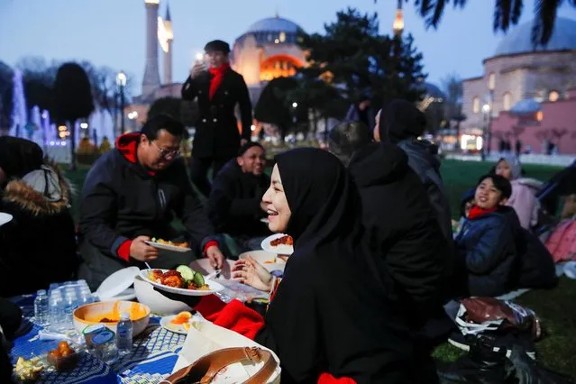 People, with the Ayasofya-i Kebir Camii or Hagia Sophia Grand Mosque in the background, have their iftar (breaking fast) meal at Sultanahmet Square during first day of the holy month of Ramadan in Istanbul, Turkey on March 23, 2023. (Photo by Dilara Senkaya/Reuters)