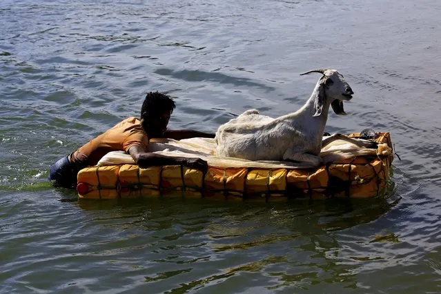 An Ethiopian man who fled the ongoing fighting in Tigray region holds on to jerrycans used as a floater for his goat as they cross the Setit river on the Sudan-Ethiopia border in the Hamdayet village, in eastern Kassala state, Sudan on December 15, 2020. (Photo by Mohamed Nureldin Abdallah/Reuters)