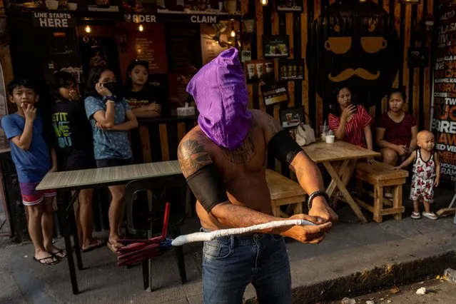 Customers at a coffee shop watch as Filipino Catholic devotees perform self-flagellation along a street on Maundy Thursday in Manila, Philippines on April 6, 2023. (Photo by Eloisa Lopez/Reuters)