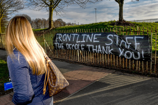 An NHS worker walks past a banner supporting NHS staff outside Salford Royal Hospital on March 22, 2020 in Manchester, UK. Coronavirus (COVID-19) has spread to at least 182 countries, claiming over 13,069 lives and infecting more than 308,592 people. There have now been 5,018 diagnosed cases in the UK and 233 deaths. (Photo by Anthony Devlin/Getty Images)