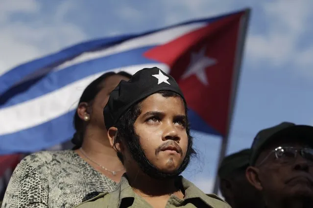 Brian Gracia, 11, dressed as revolutionary leader Ernesto “Che” Guevara, watches a convoy of military trucks, re-enacting the triumphal 1959 march into Havana by Fidel Castro and his “Barbudos” (bearded) guerrillas, in Havana, January 8, 2015. (Photo by Reuters/Stringer)