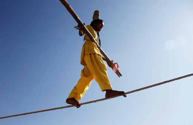 A tightrope walker performs on a rope while holding a balancing pole at Pushkar Fair, where animals, mainly camels, are brought to be sold and traded in the desert Indian state of Rajasthan, India, November 12, 2016. (Photo by Himanshu Sharma/Reuters)