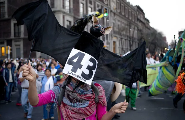 A protester holds a bat puppet with the number 43 during a march marking the fourth month since the disappearance of 43 students from a rural teachers' college, in Mexico City, Monday, January 26, 2015. Prosecutors have said police kidnapped the students on Sept. 26 in the southern state of Guerrero and handed them over to drug gang members, who killed them and burned the bodies, but protesters said Monday the government has failed to clear up doubts. (Photo by Eduardo Verdugo/AP Photo)