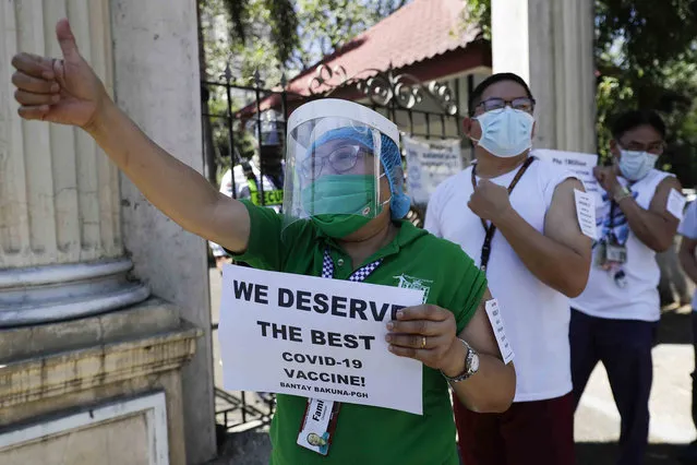 A health worker wearing a face mask and face shield gestures as they call on the government to give them a vaccine with the safest, highest efficacy and effectivity during a a protest outside the Philippine General Hospital in Manila, Philippines on Friday, February 26, 2021. The group is opposing a plan by the government to have health workers vaccinated with China's Sinovac which is expected to arrive this weekend. (Photo by Aaron Favila/AP Photo)