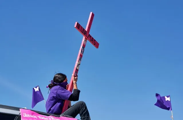 A mother seen atop a vehicle holding a cross with a sign reading “Not one more” during a caravan demanding an end to violence against women and femicide, ahead of a Women's Day protest, in Ciudad Juarez, Mexico on March 7 , 2021. (Photo by Mahe Elipe/Reuters)