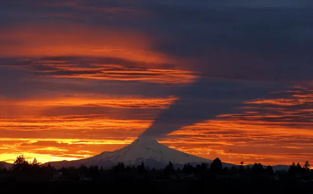 The rising sun cast a shadow of Mount Hood on the clouds Wednesday, February 24, 2016, in Portland, Ore. (Photo by Mike Zacchino/The Oregonian via AP Photo)